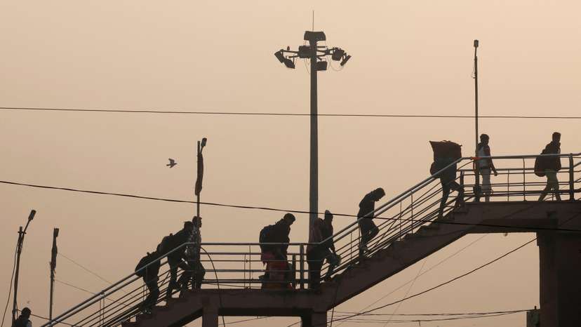 People walk on the stairs of a footbridge as the sky is enveloped in smog