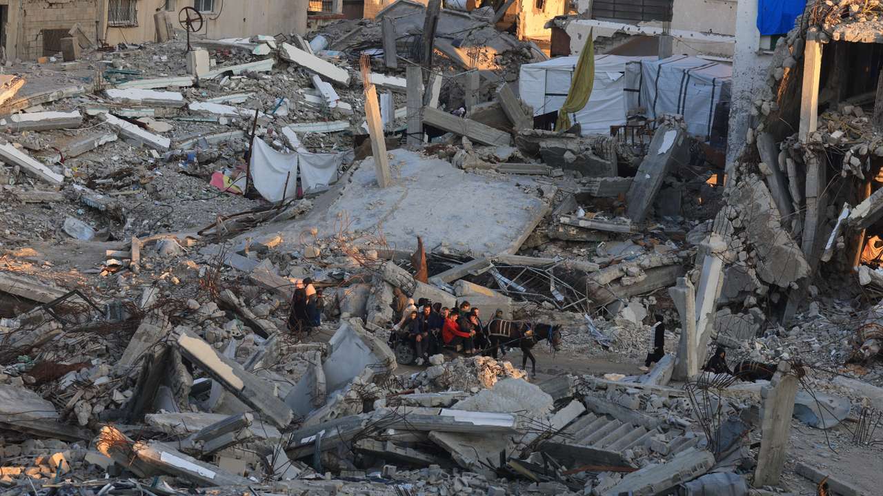 Palestinians move past the rubble of residential buildings destroyed during the war, in Gaza City