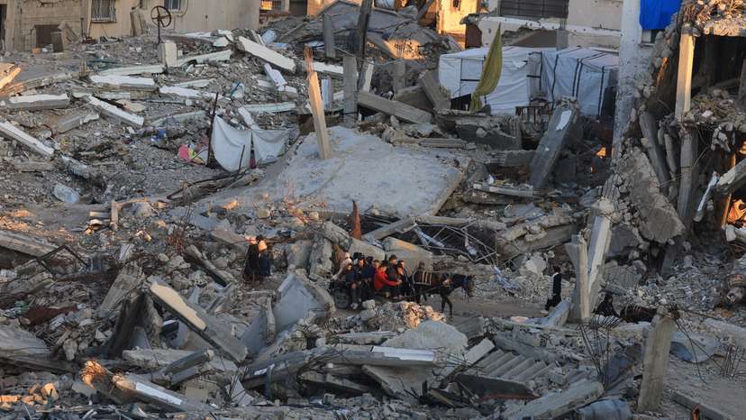 Palestinians move past the rubble of residential buildings destroyed during the war, in Gaza City