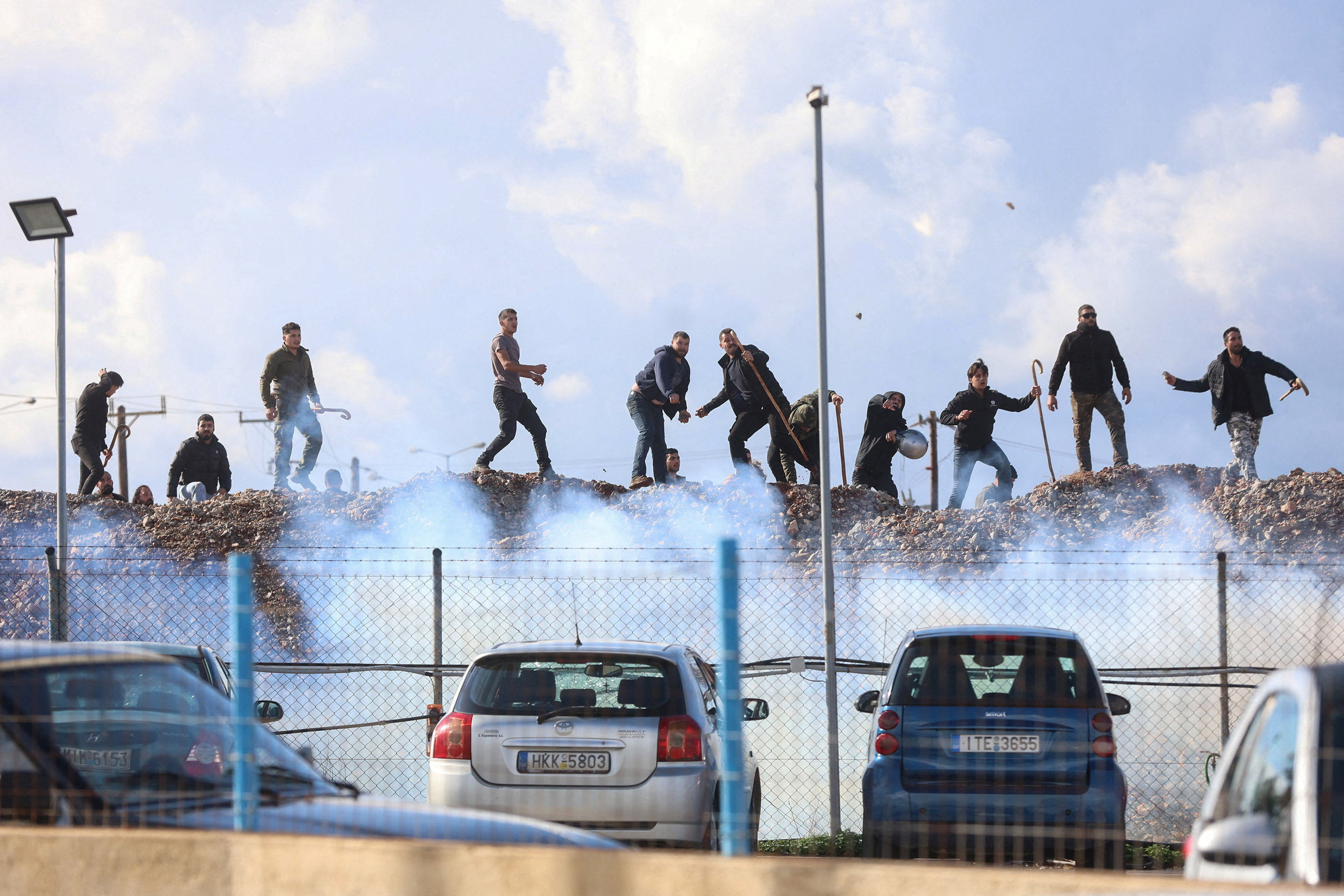 Greek farmers hurl stones amid tear gas at the Heraklion International Airport, in Heraklion
