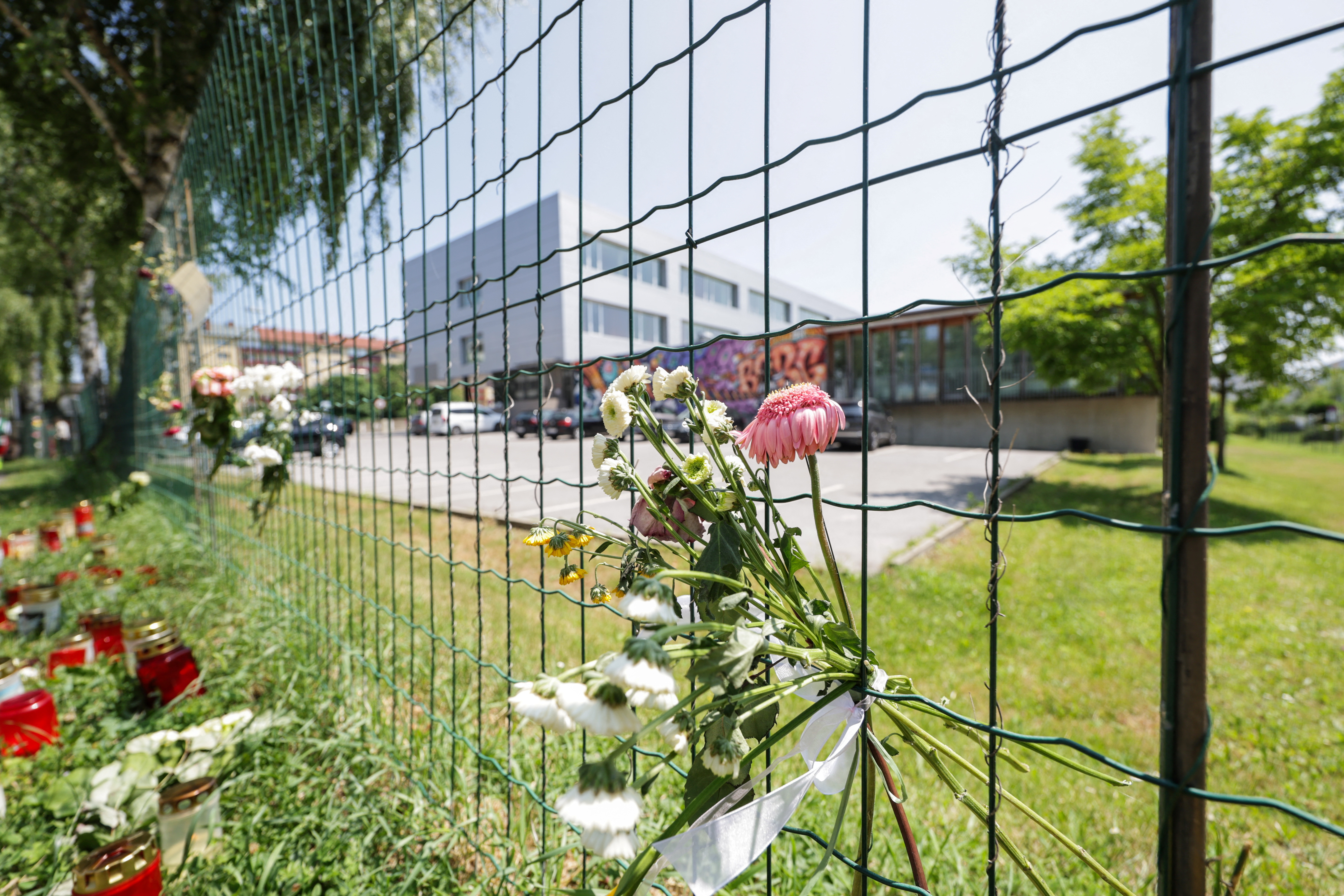 Flowers and candles are seen in front of the fences of the school in Graz
