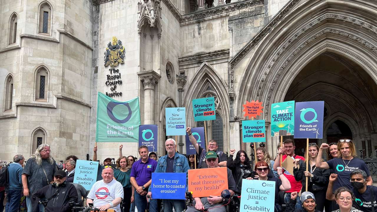 Supporters of environmental group Friends of the Earth hold signs outside the Royal Courts of Justice, in London