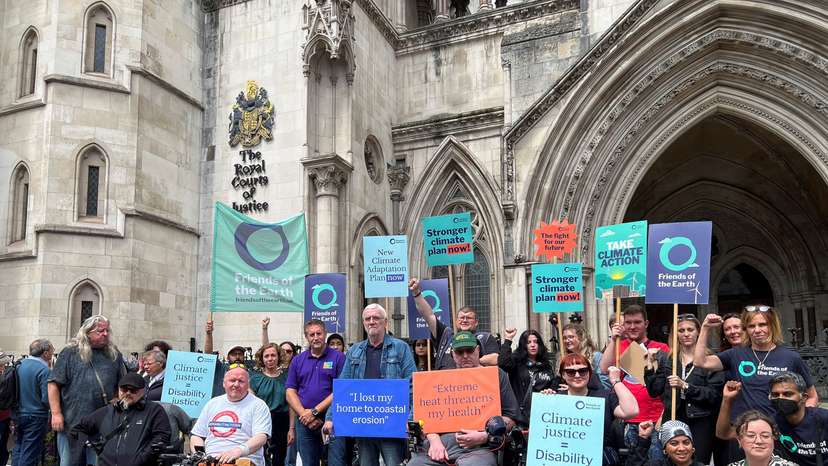 Supporters of environmental group Friends of the Earth hold signs outside the Royal Courts of Justice, in London