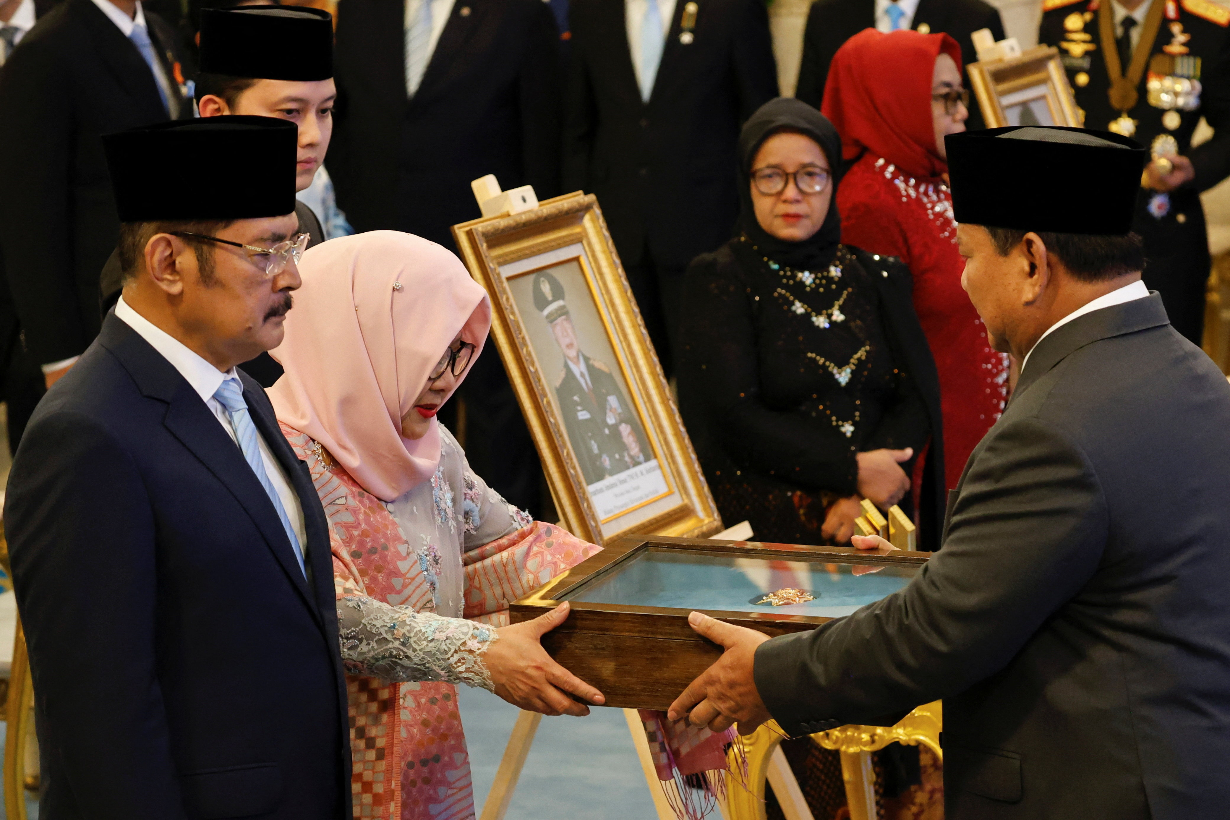Indonesia's President Prabowo Subianto gives a plaque to Siti Hardiyanti Rukmana, daughter of the former Indonesian president Suharto, as he receives the title of a national hero during National Heroes' Day at the Merdeka Palace in Jakarta