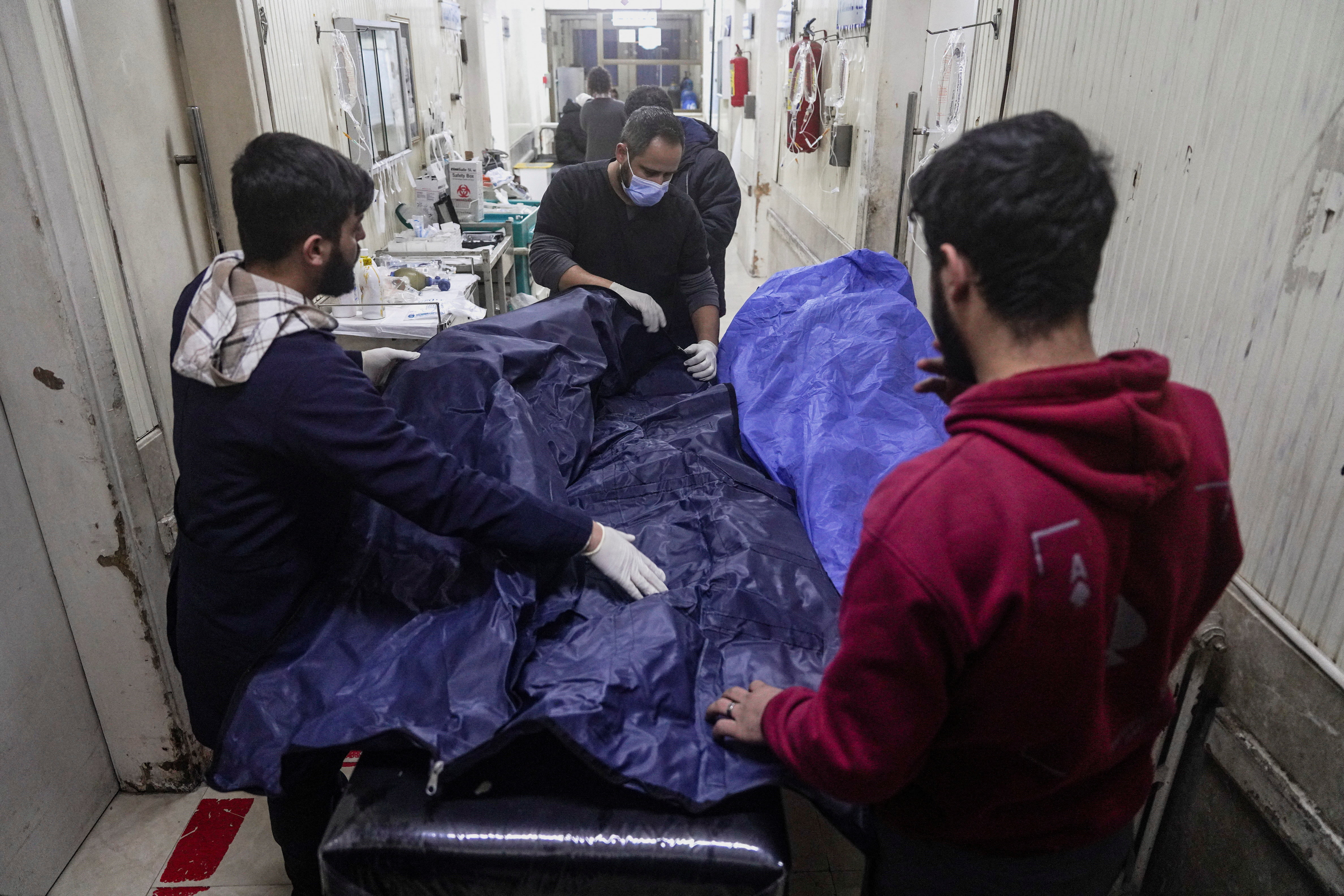 Paramedics place a body into a body bag at a hospital in Aleppo