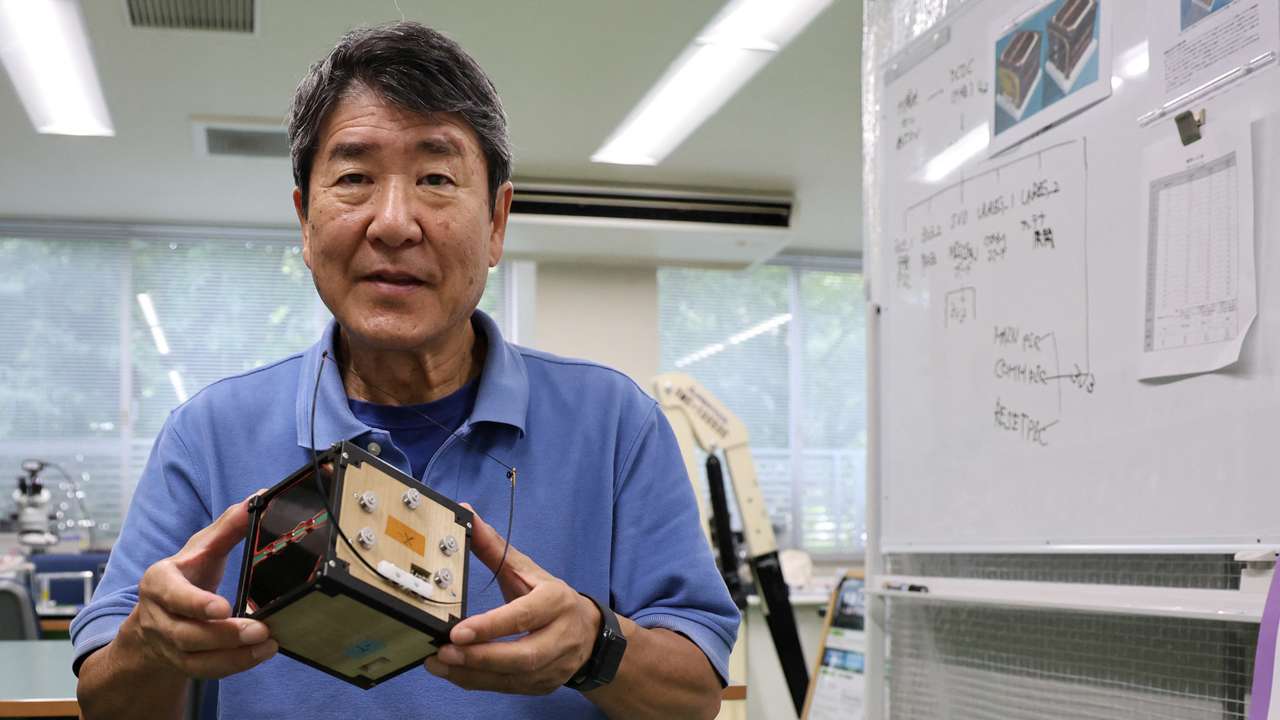 Takao Doi holds an engineering model of LignoSat during an interview with Reuters at his laboratory at Kyoto University in Kyoto