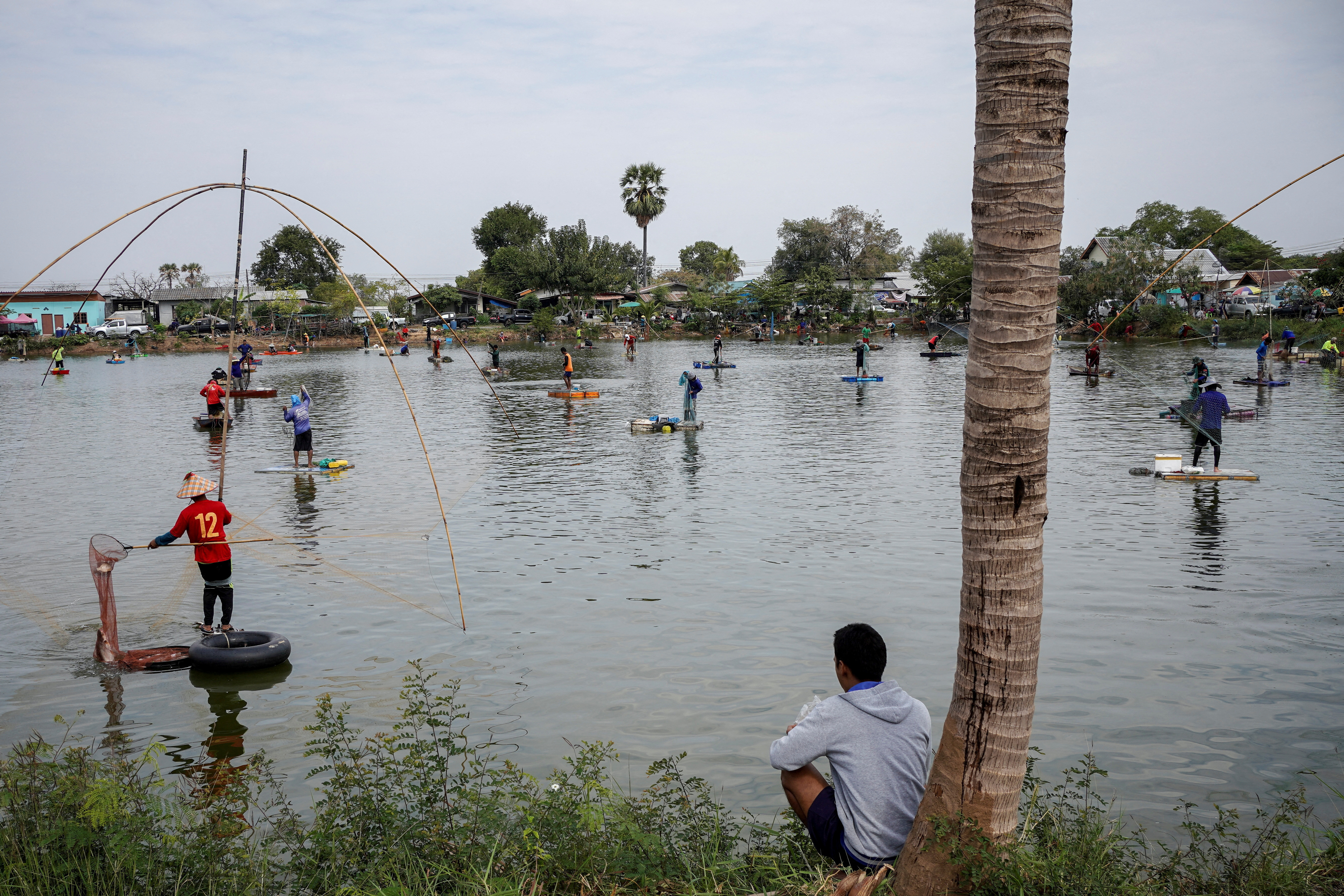 FILE PHOTO: People fish in a pond on the outskirts of Buriram province