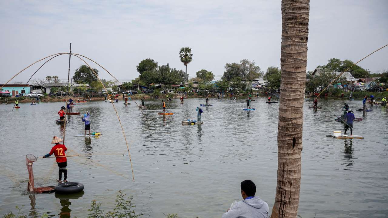 FILE PHOTO: People fish in a pond on the outskirts of Buriram province