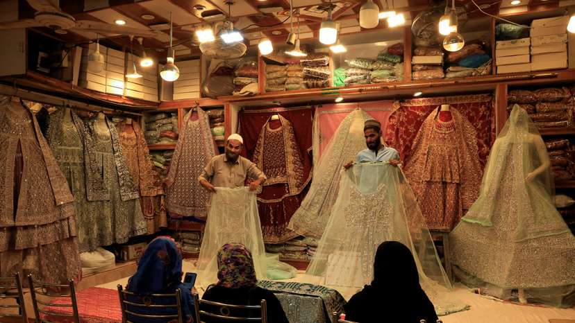 Shopkeepers display bridal dresses to customers at a shop in cloth market in Karachi