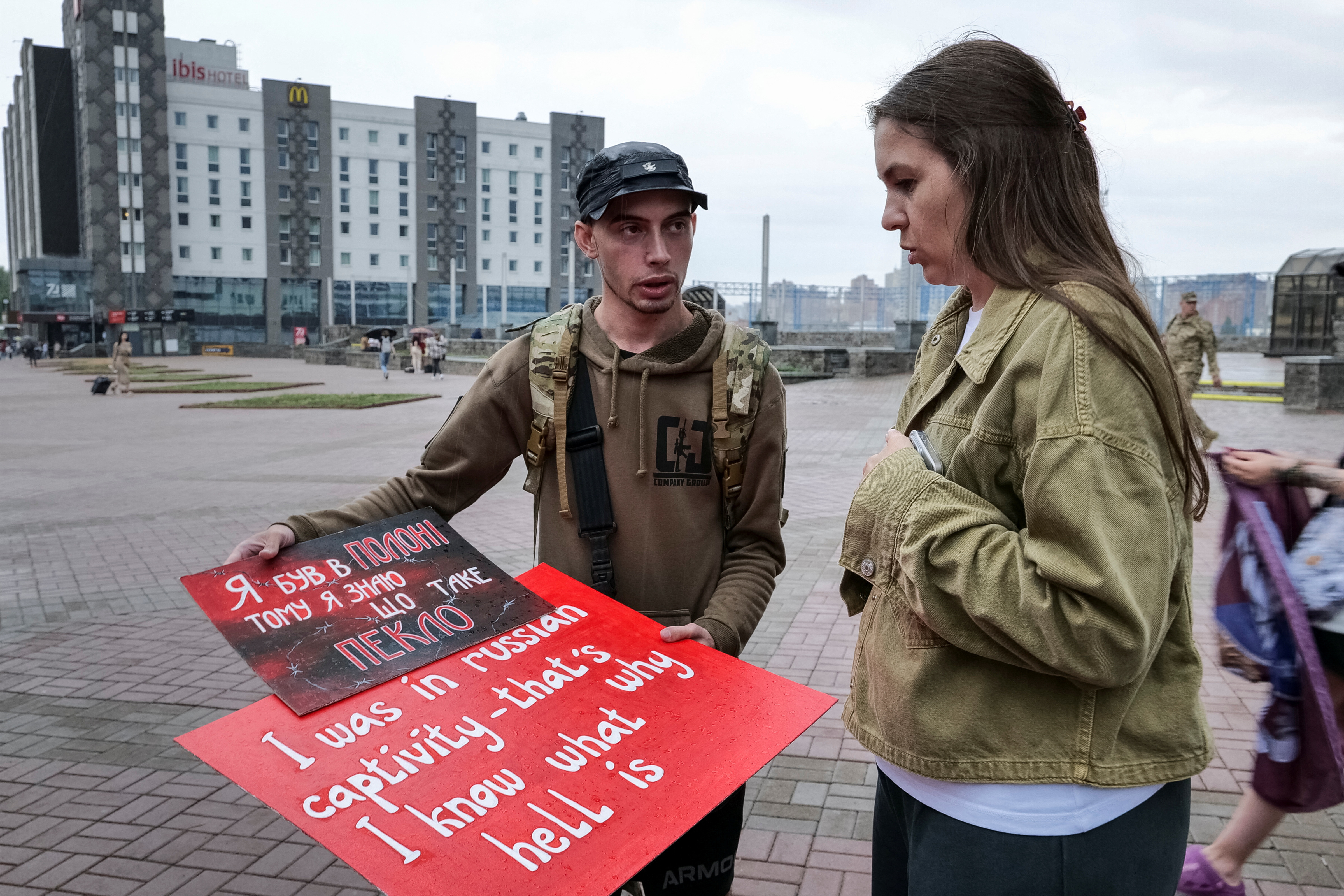 Svitlana Bilous and Illia Illiashenko look at posters before their bus tour to Switzerland to advocate for Ukrainian soldiers in Russian captivity in Kyiv