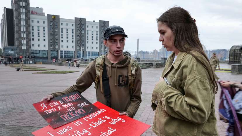 Svitlana Bilous and Illia Illiashenko look at posters before their bus tour to Switzerland to advocate for Ukrainian soldiers in Russian captivity in Kyiv
