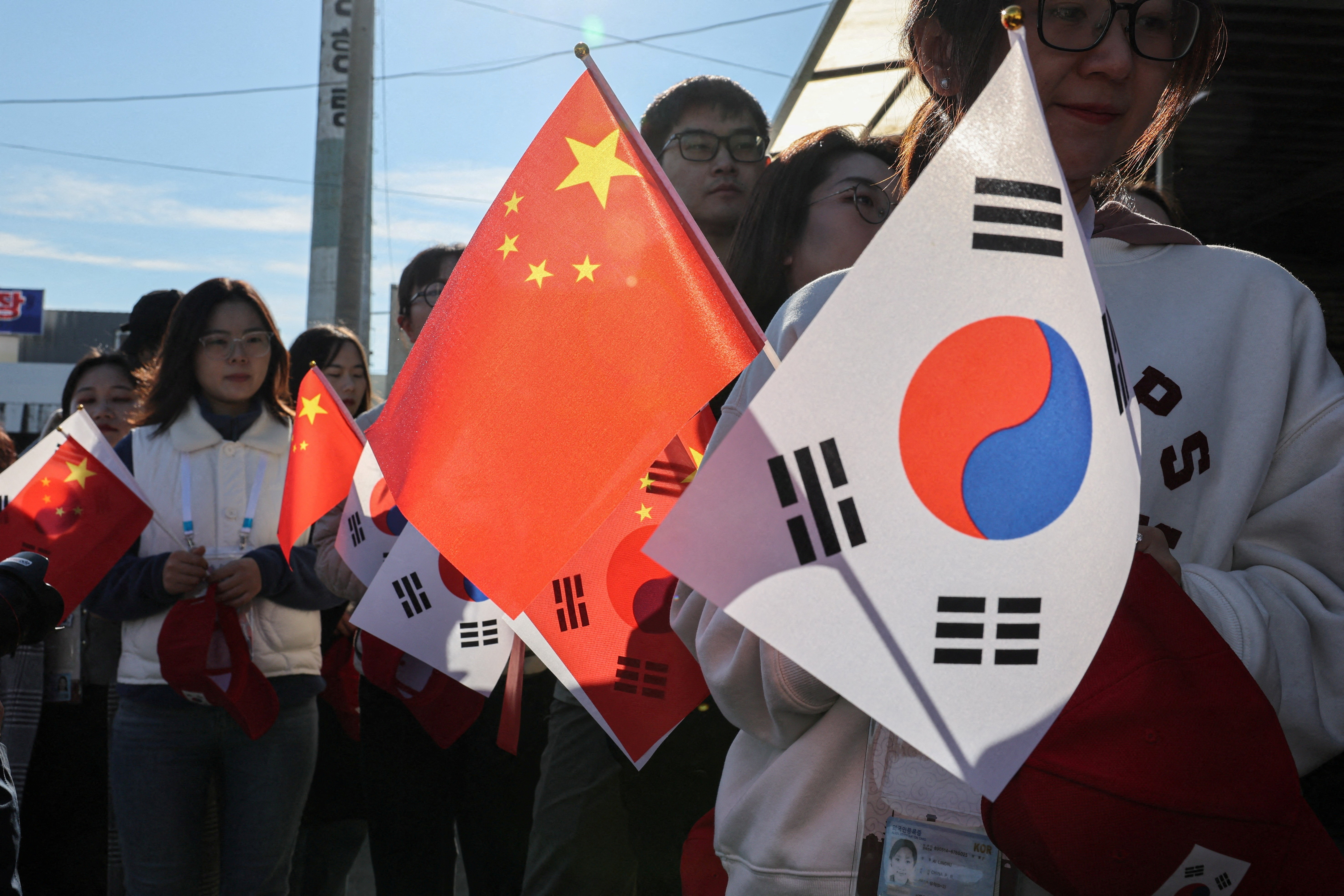 FILE PHOTO: Pro-China supporters hold China and South Korea flags near Gimhae International Airport in Busan