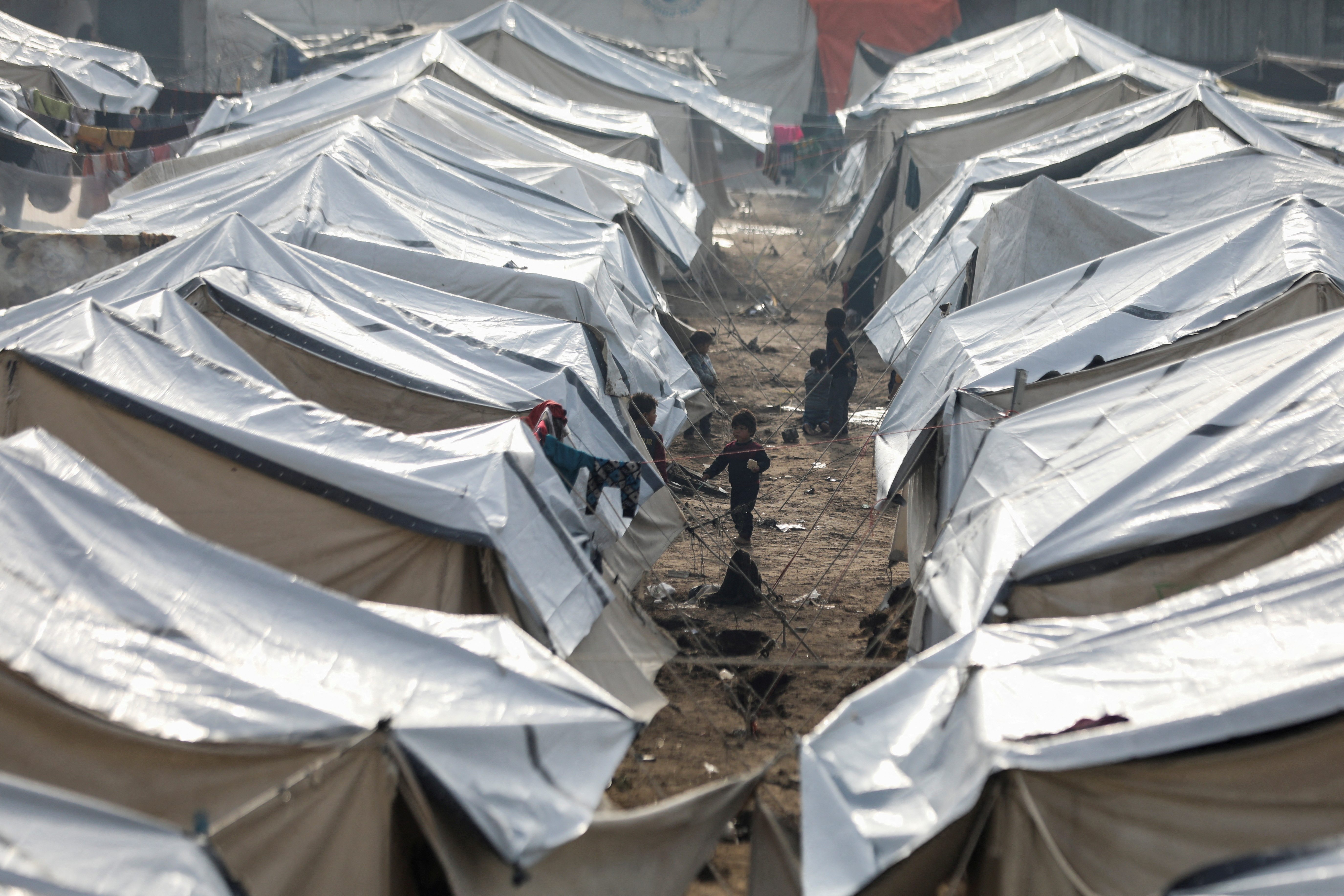 Displaced Palestinians fix their tents following rainfall, in Gaza City
