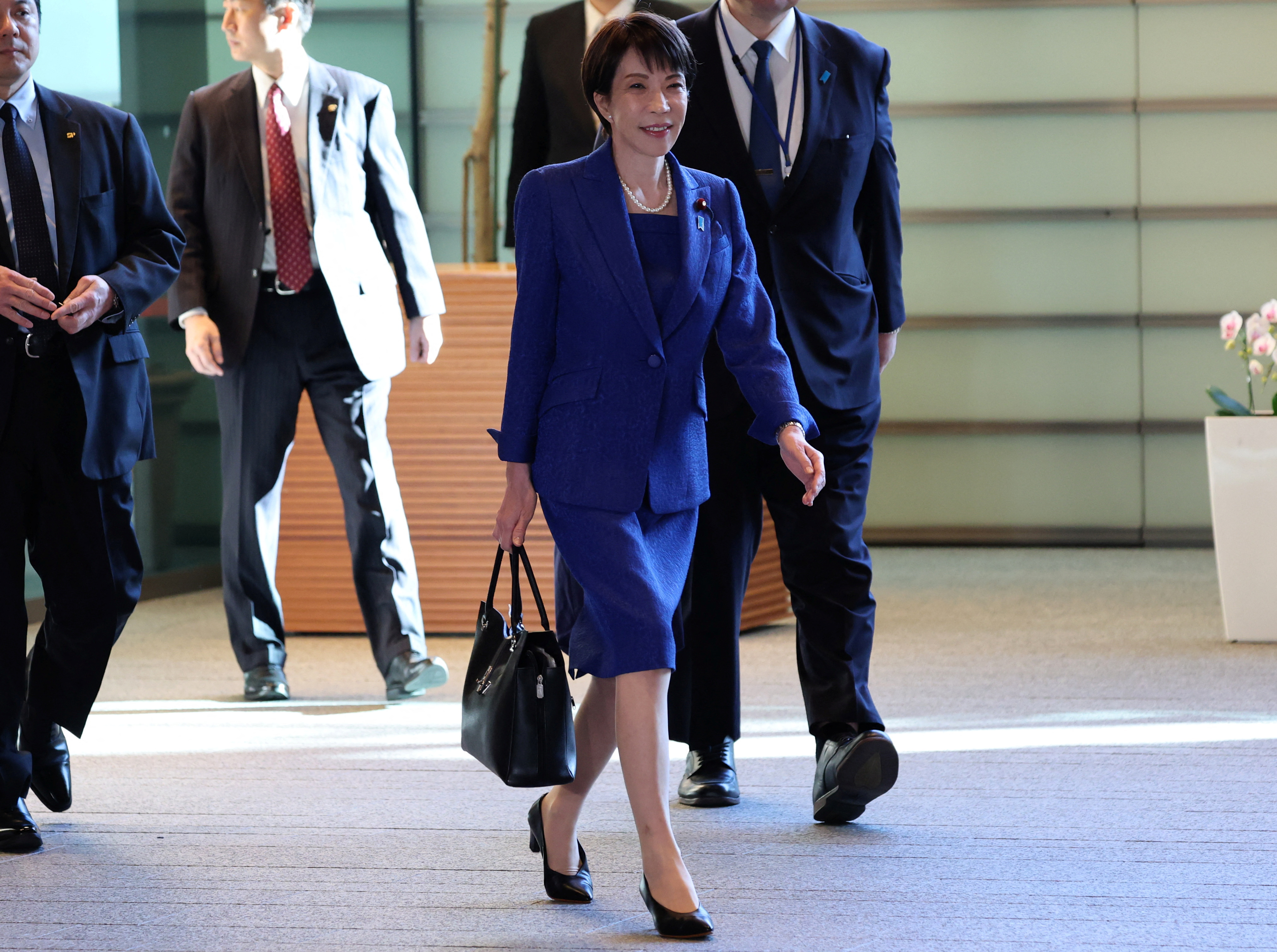 Japan's Prime Minister Sanae Takaichi carries Japanese leather goods maker Hamano’s tote bag as she arrives at the Prime Minister's Office in Tokyo