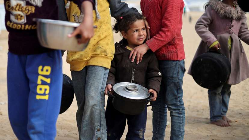 FILE PHOTO: Displaced Palestinian children wait to receive free food at a tent camp, amid food shortages, in Rafah