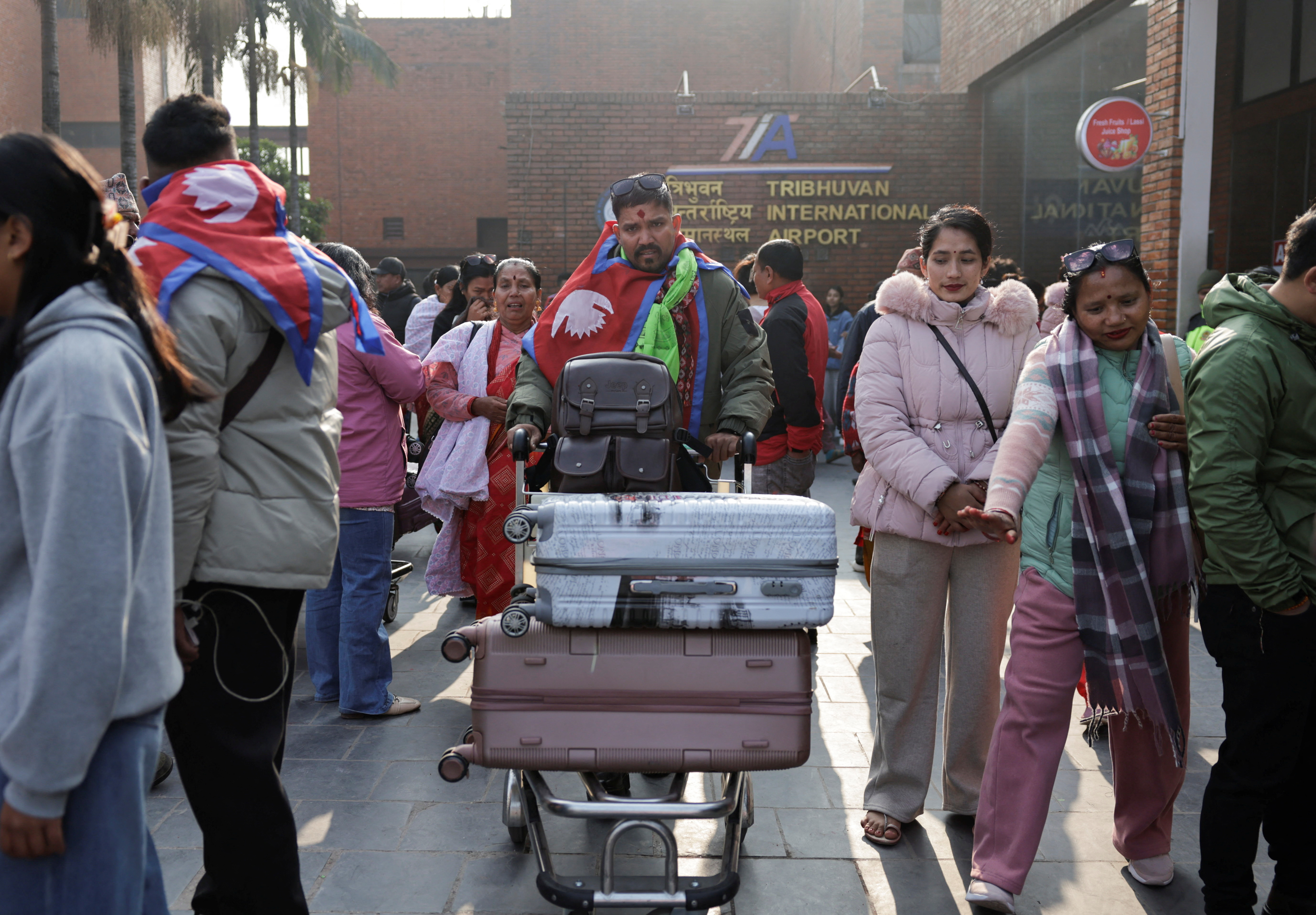 Ramesh Bahadur B.K. Nimaile is followed by his weeping mother Dudkala Nimaile and wife Meena Nimale, as he heads towards the departure terminal for a job in Romania, at Tribhuvan International Airport
