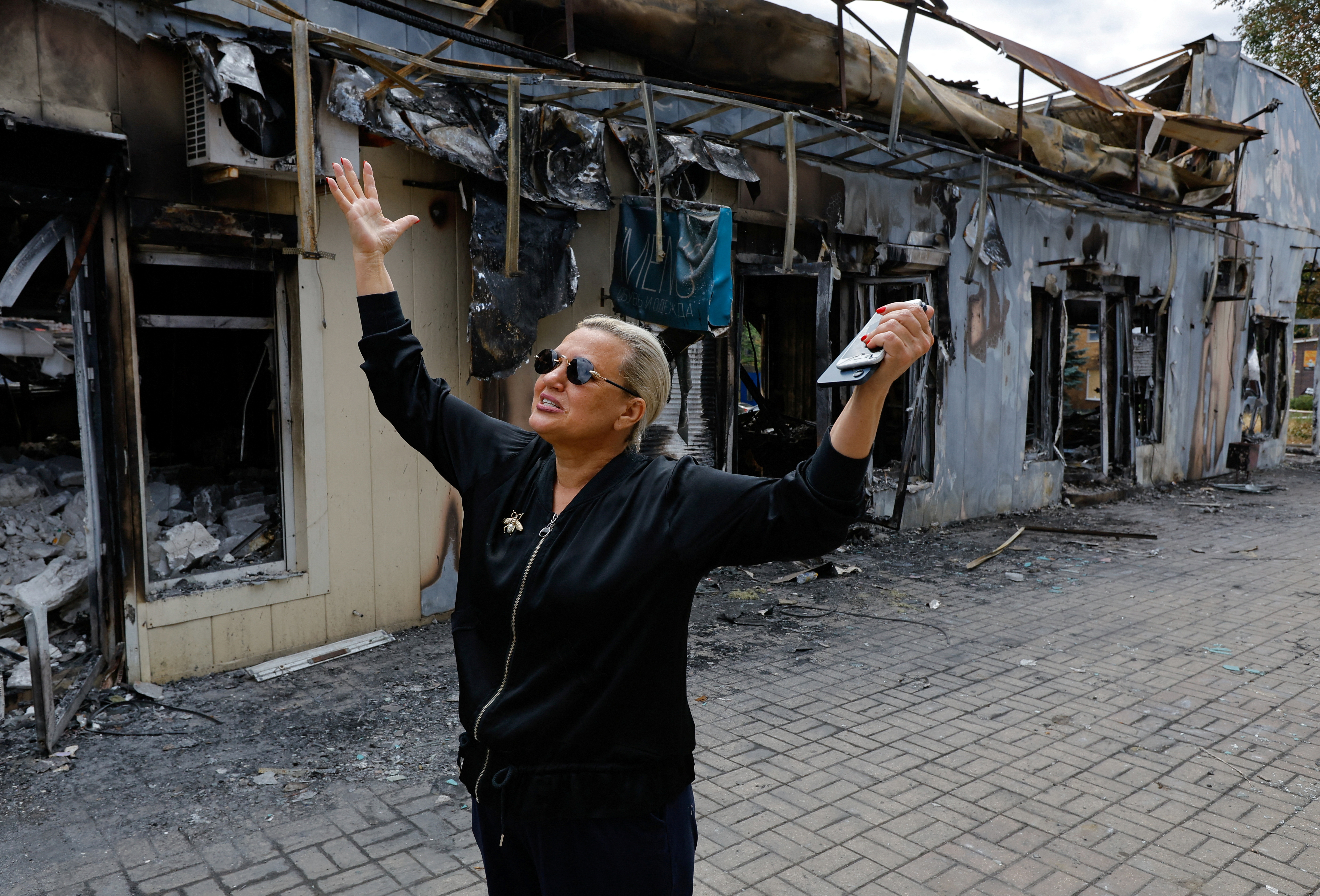 A shop owner shows the damage to her store following the shelling of a market in Donetsk