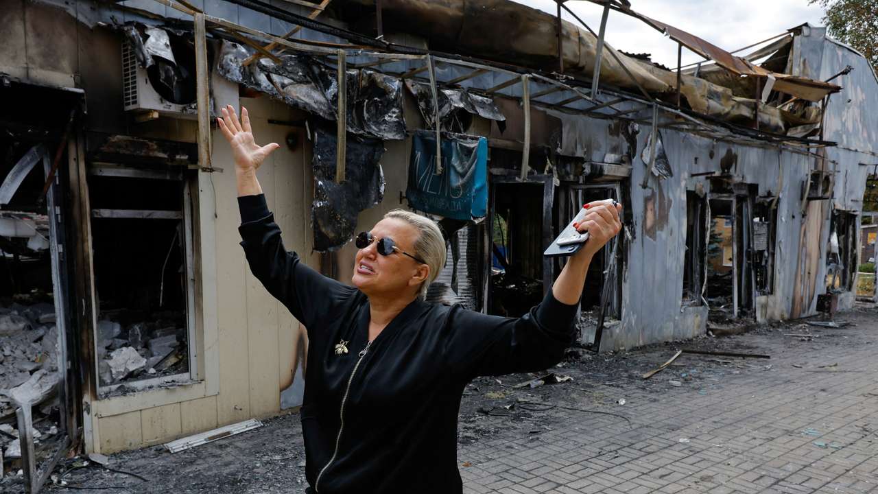 A shop owner shows the damage to her store following the shelling of a market in Donetsk