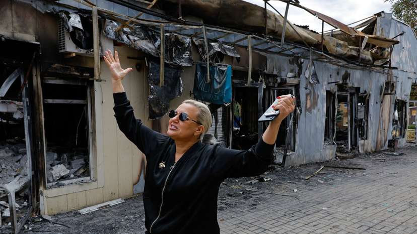 A shop owner shows the damage to her store following the shelling of a market in Donetsk