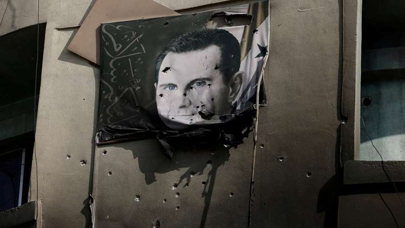 FILE PHOTO: A picture of Bashar al-Assad, damaged by bullets, hangs on the wall of a burnt building of Criminal Security department, after Syria's Bashar al-Assad was ousted, in Damascus