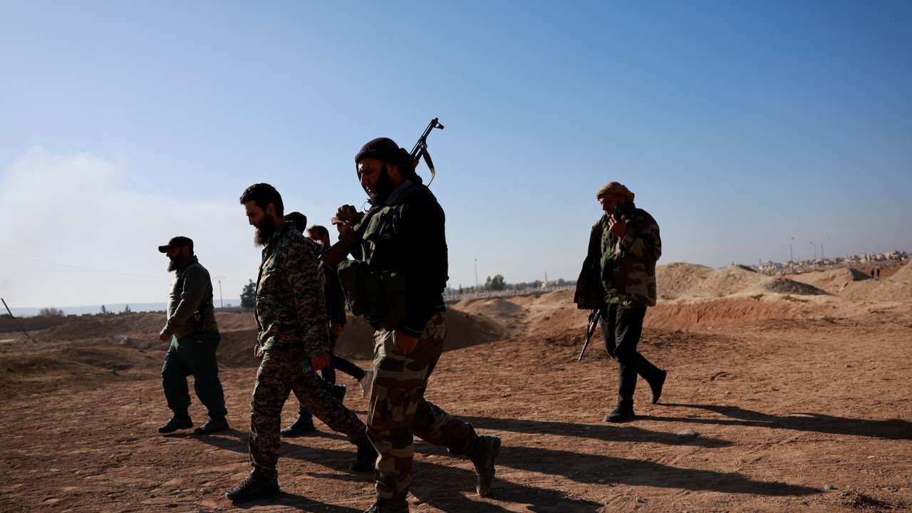 Fighters of the ruling Syrian body walk at the site of a mass grave from the rule of Syria's Bashar al-Assad, in Najha