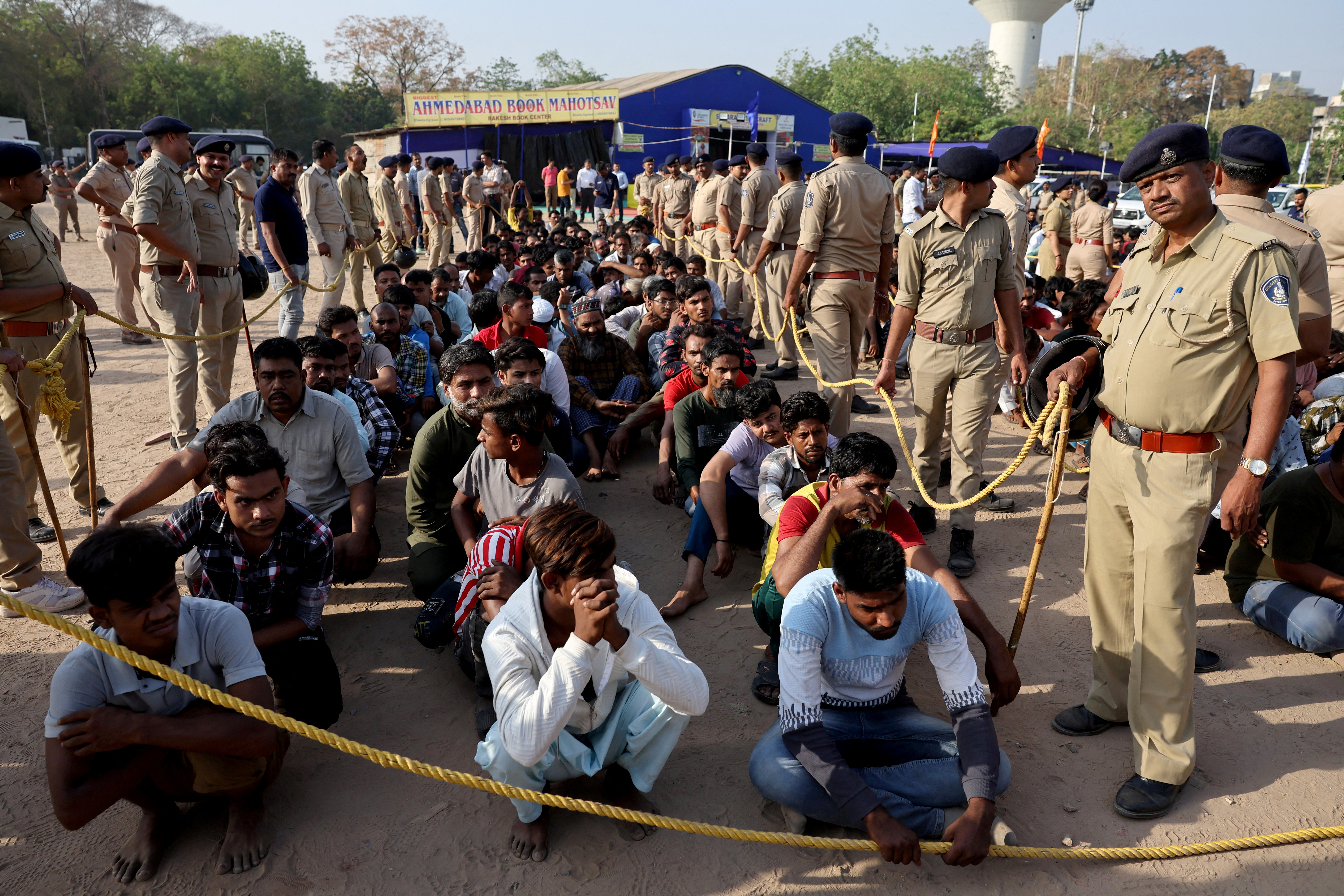 FILE PHOTO: Police officers stand next to men they believe to be undocumented Bangladeshi nationals after they were detained during raids in Ahmedabad
