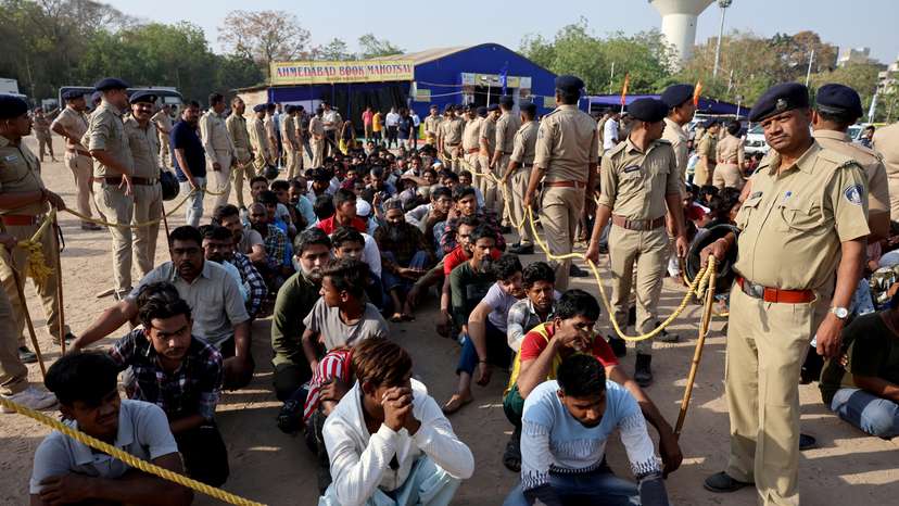 FILE PHOTO: Police officers stand next to men they believe to be undocumented Bangladeshi nationals after they were detained during raids in Ahmedabad