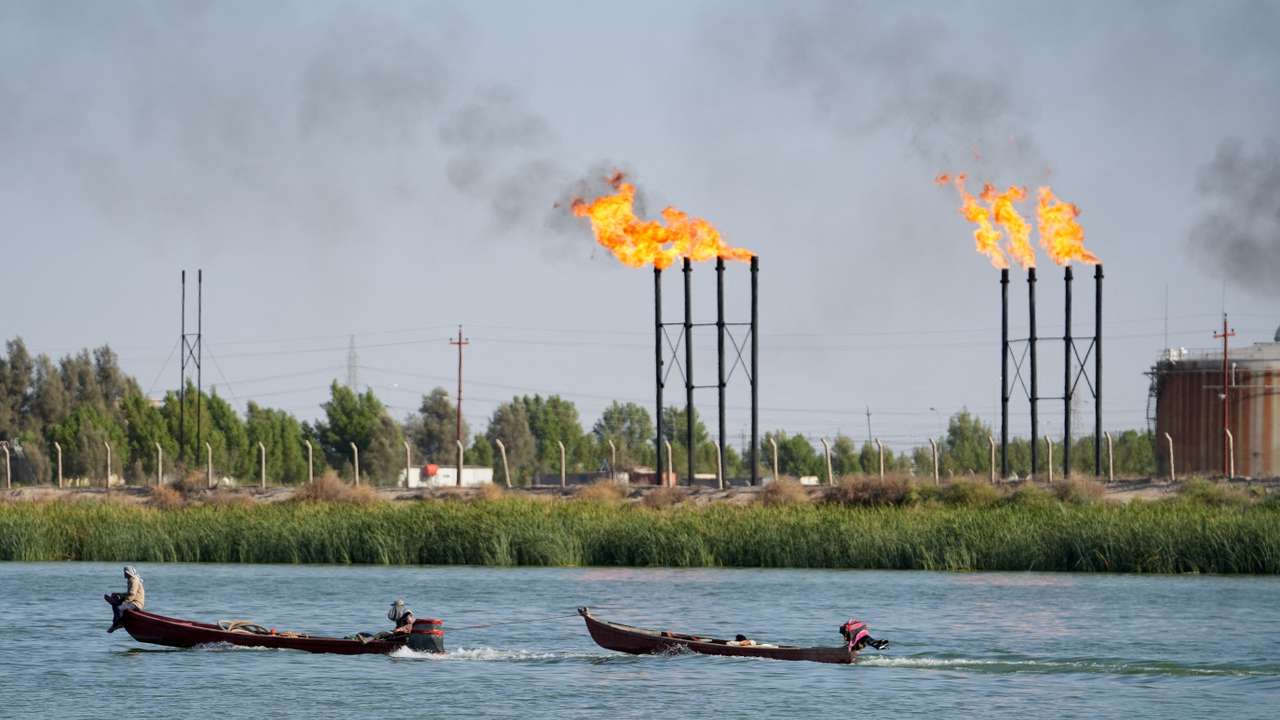People navigate boats near Nahr Bin Umar oil field, in Basra