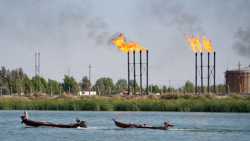 People navigate boats near Nahr Bin Umar oil field, in Basra