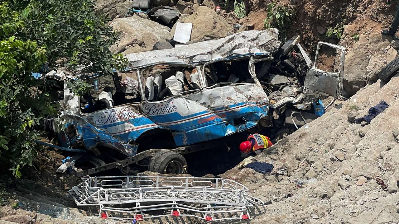 Rescue worker operates on the site of a damaged passenger bus, after it plunged into a deep ravine in Kahuta