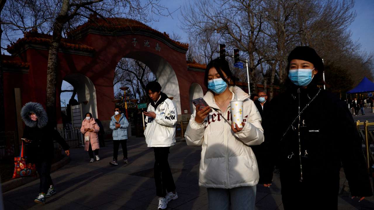 FILE PHOTO: People wearing masks walk on street in Beijing
