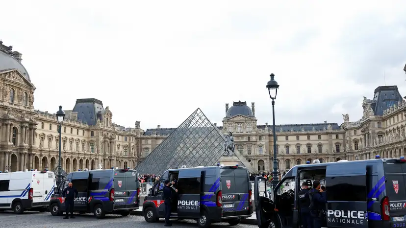 French police vans are parked near the glass Pyramid of the Louvre Museum