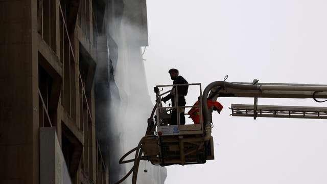 Fireman controls waterpipes as he works after a fire broke out in the Pakistan Stock Exchange building in Karachi