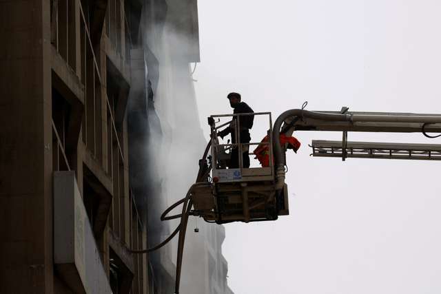 Fireman controls waterpipes as he works after a fire broke out in the Pakistan Stock Exchange building in Karachi