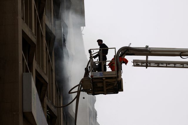 Fireman controls waterpipes as he works after a fire broke out in the Pakistan Stock Exchange building in Karachi