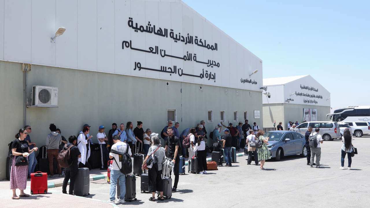 Expats, including diplomats from different nationalities, who were stranded in West Bank and Israel, wait as they hold belongings while being evacuated through the King Hussein Bridge crossing, in South Shuna