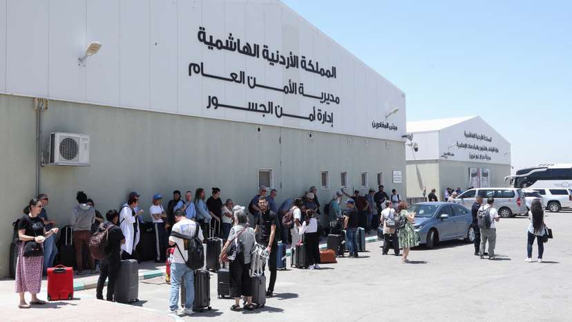 Expats, including diplomats from different nationalities, who were stranded in West Bank and Israel, wait as they hold belongings while being evacuated through the King Hussein Bridge crossing, in South Shuna