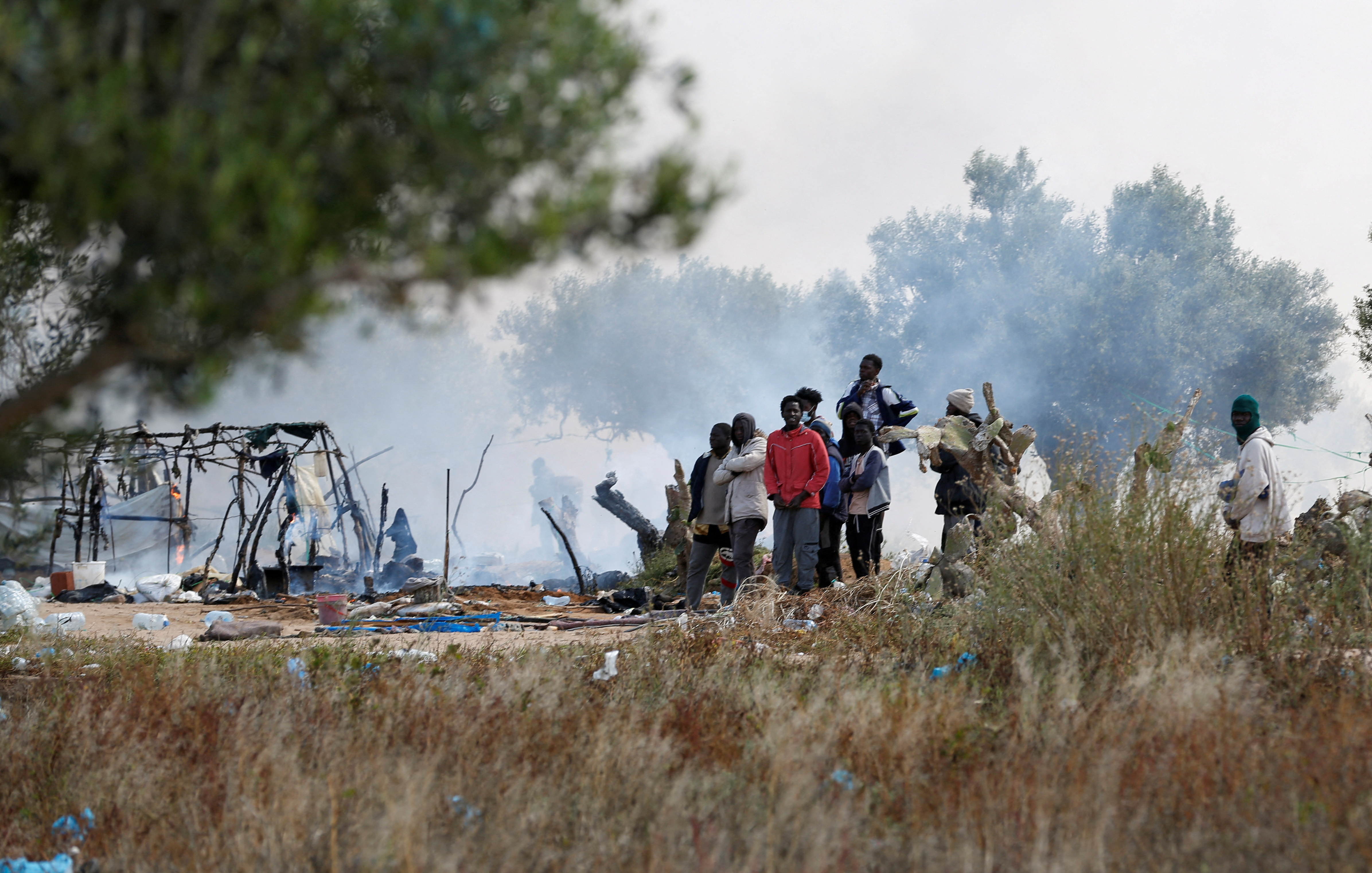 FILE PHOTO: Migrants gather together near burnt tents as Tunisian authorities have dismantled makeshift camps housing sub-Saharan African migrants