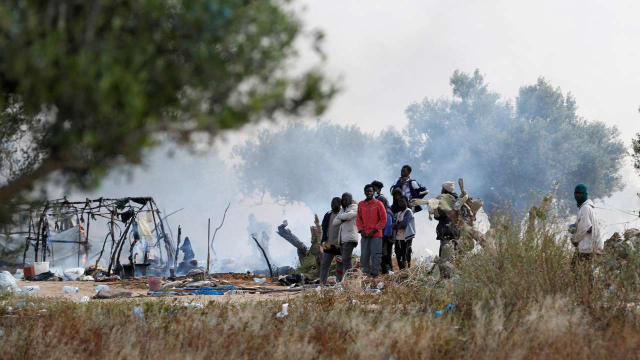 FILE PHOTO: Migrants gather together near burnt tents as Tunisian authorities have dismantled makeshift camps housing sub-Saharan African migrants