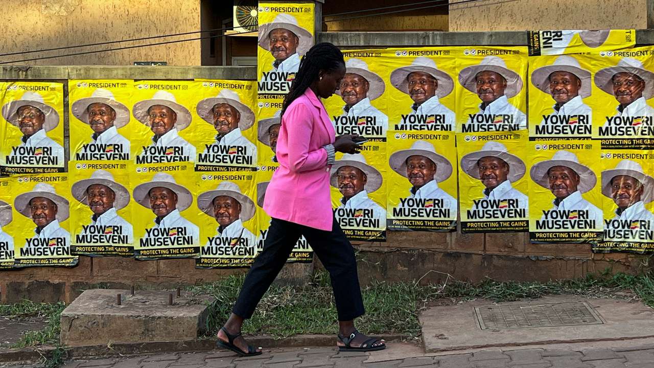 A woman walks past campaign posters of Uganda's President and the leader of ruling NRM party, Yoweri Museveni, ahead of the general election in Kampala