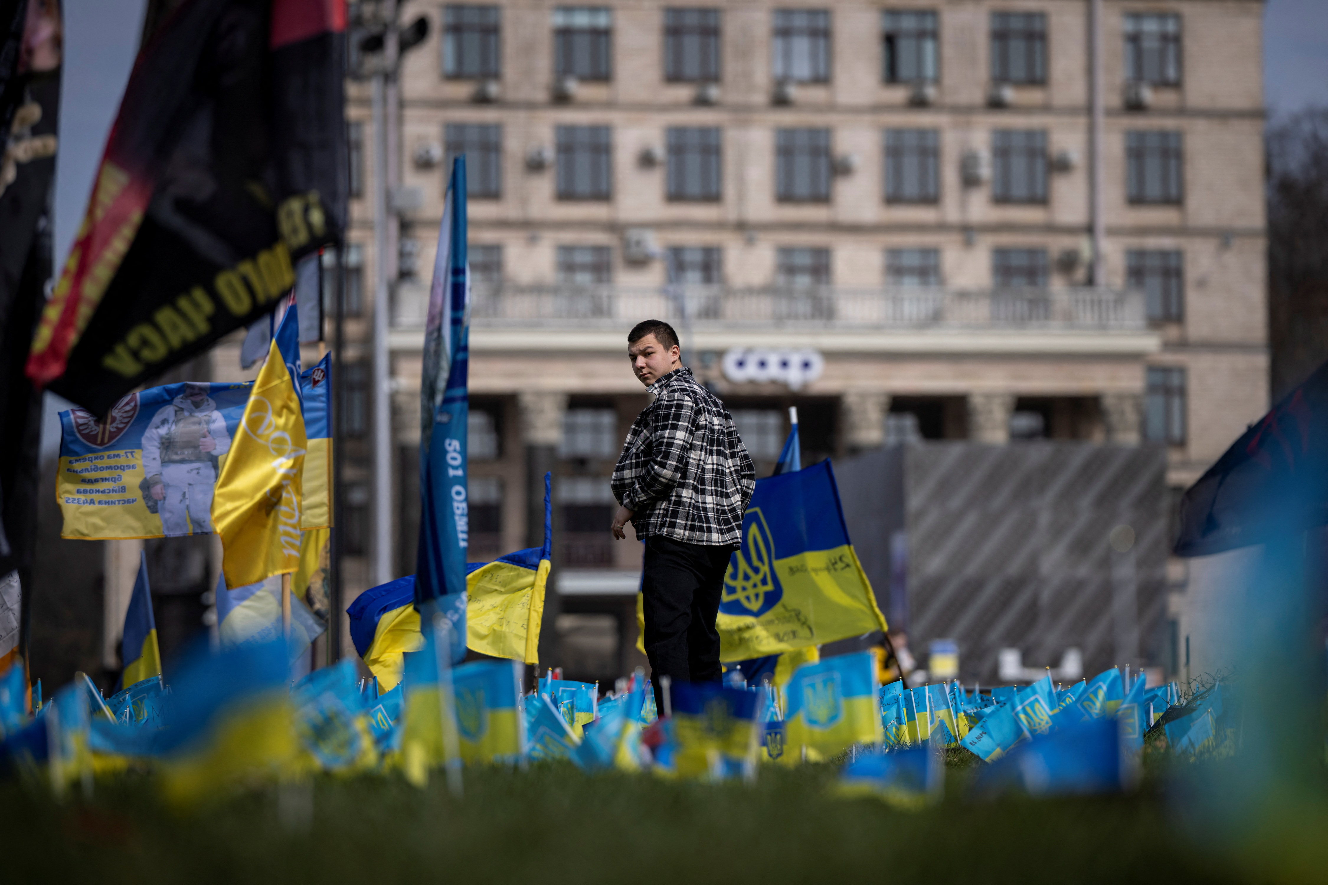 A man walks past Ukrainian flags at a memorial commemorating fallen servicemen who fought against Russia’s  invasion of Ukraine, in Khreshchatyk Street in Kyiv