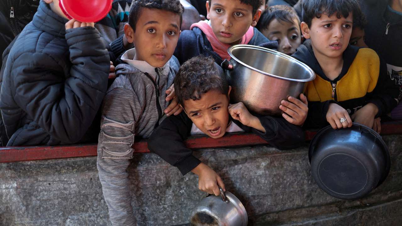 FILE PHOTO: Palestinians wait to receive food cooked by a charity kitchen amid shortages, in Rafah