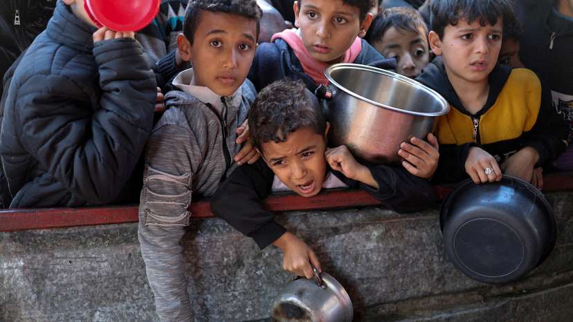 FILE PHOTO: Palestinians wait to receive food cooked by a charity kitchen amid shortages, in Rafah