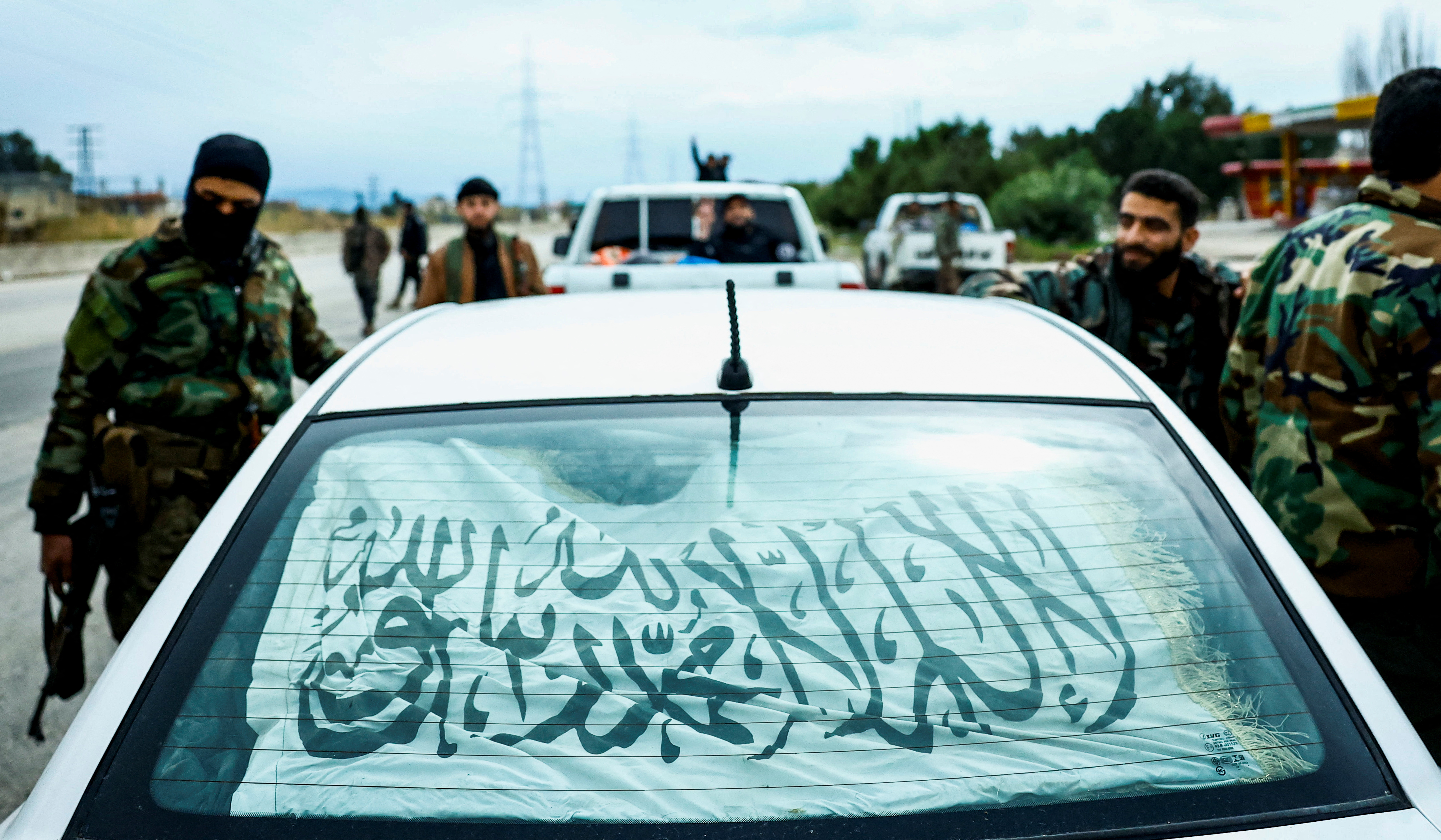 Syrian security forces stand alongside a vehicle on  on the Latakia-Jablah highway in western Syria