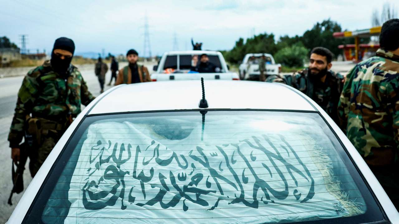 Syrian security forces stand alongside a vehicle on on the Latakia-Jablah highway in western Syria