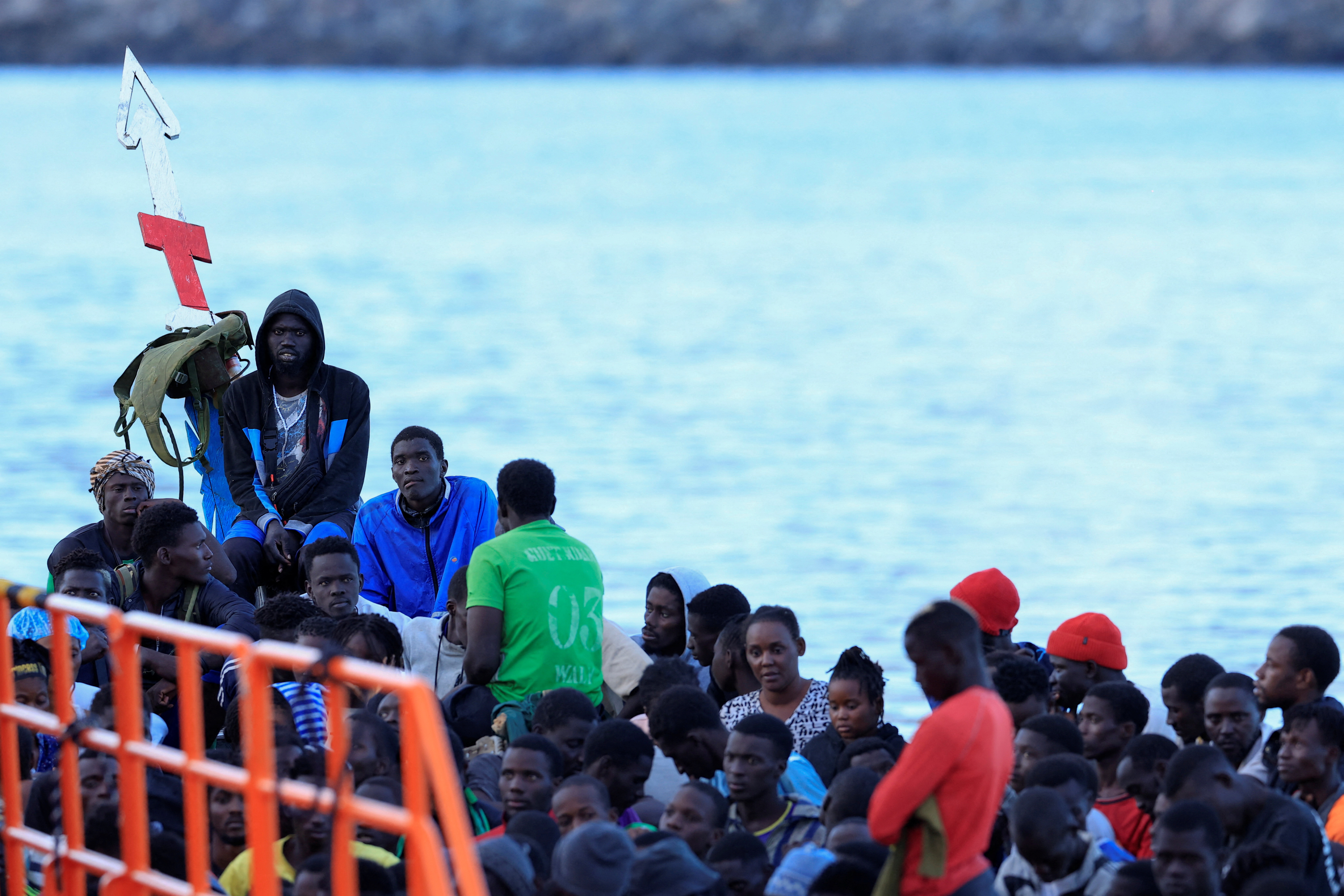 Several migrants wait to disembark from a wooden boat in the port of Arguineguin