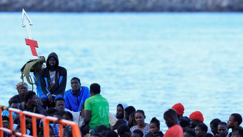 Several migrants wait to disembark from a wooden boat in the port of Arguineguin