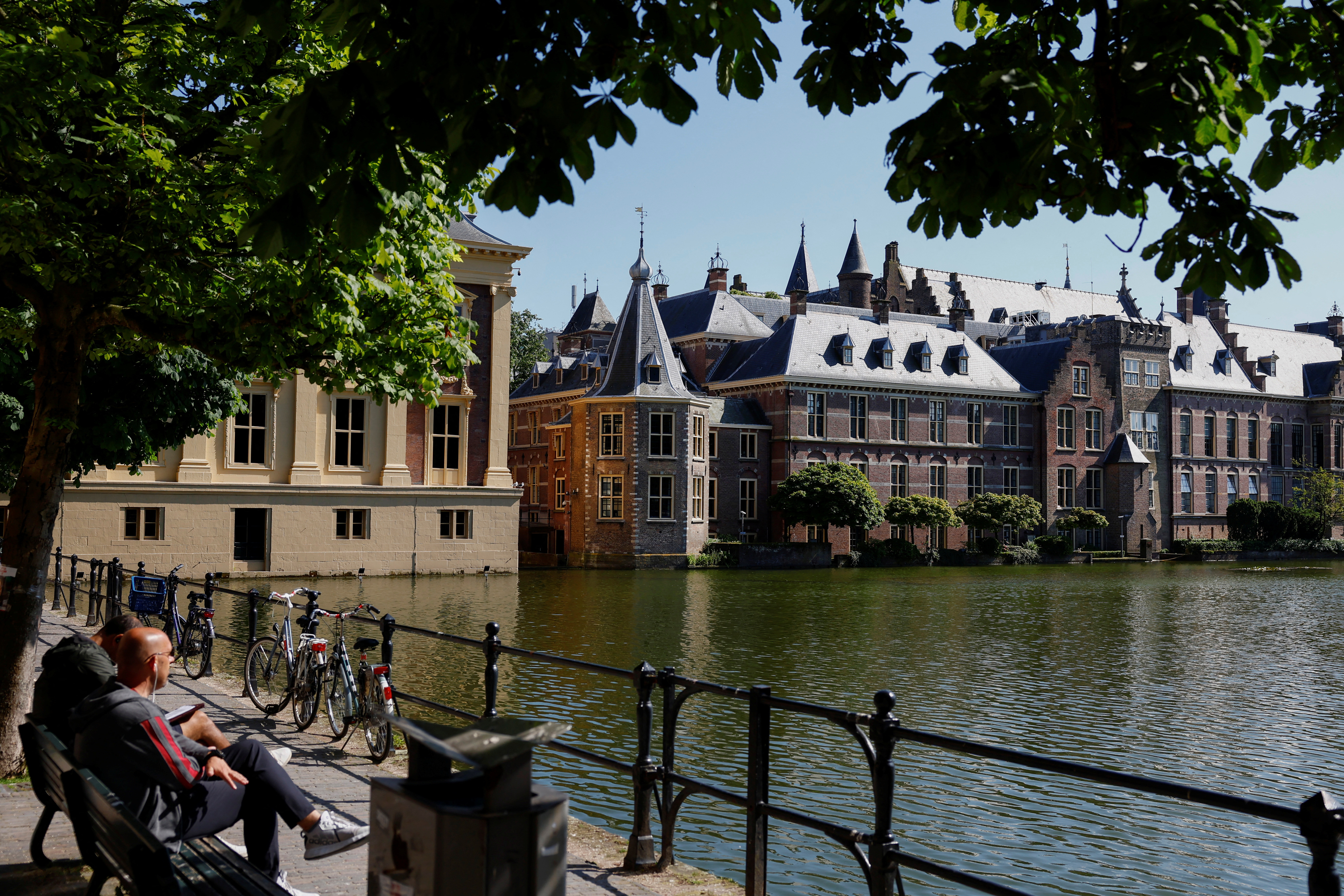 People sit on a bench with a view of the parliament building, ahead of the elections across 27 European Union member states, in the Hague