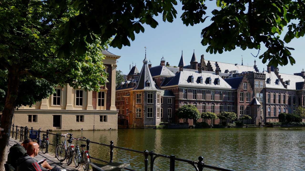 People sit on a bench with a view of the parliament building, ahead of the elections across 27 European Union member states, in the Hague