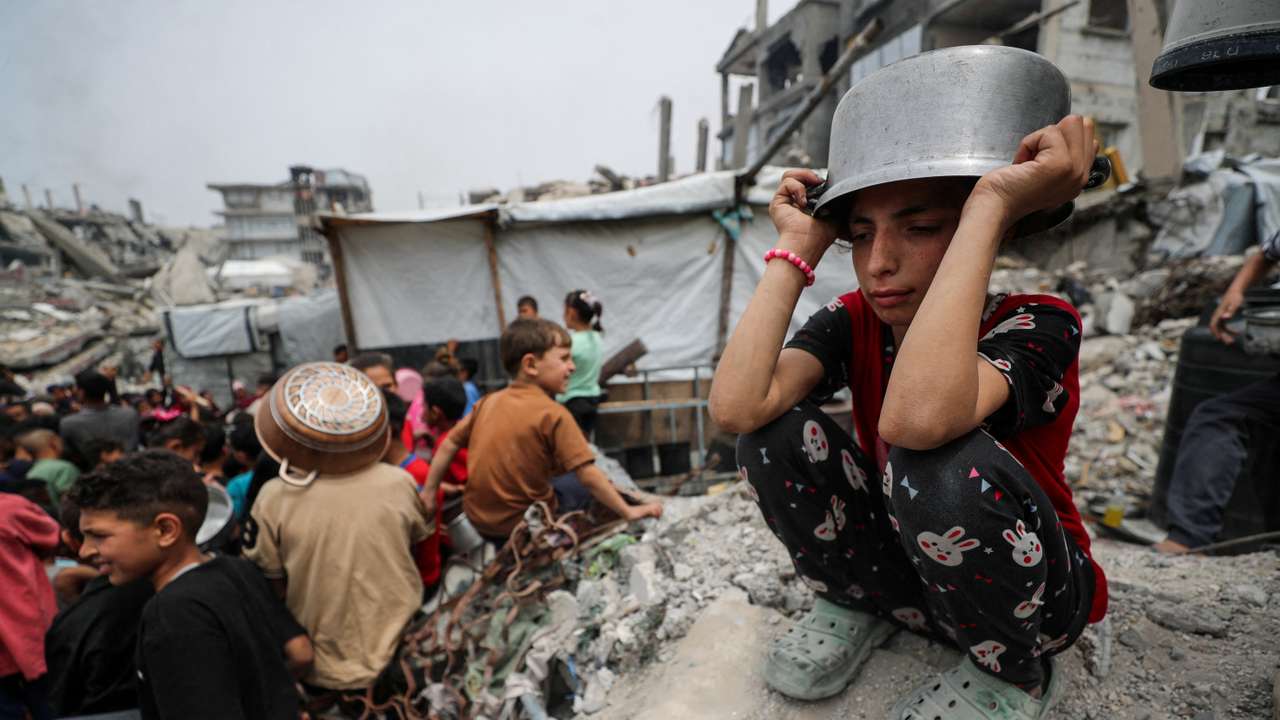 FILE PHOTO: Palestinians receive food cooked by a charity kitchen, in Beit Lahia